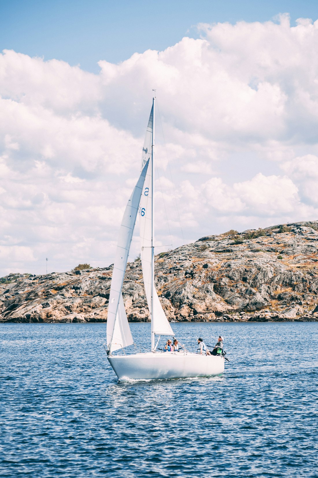 Velero blanco navegando junto a la costa
